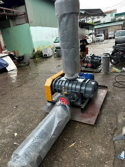 Máy thổi khí Roots RL trên bệ, nắp che dây đai màu vàng, hai ống giảm thanh bọc nilon
